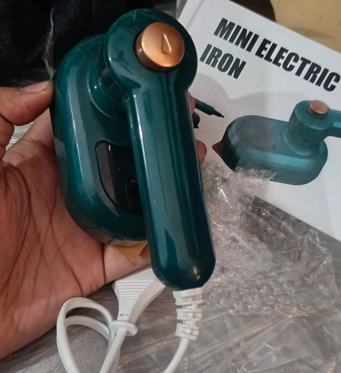 Mini electric steam iron in use on shirt fabric